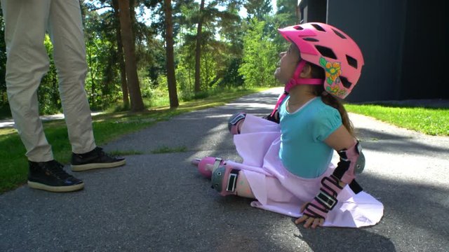 First skating. Young Mum Helps her Little Daughter to Skate on Roller Skates.