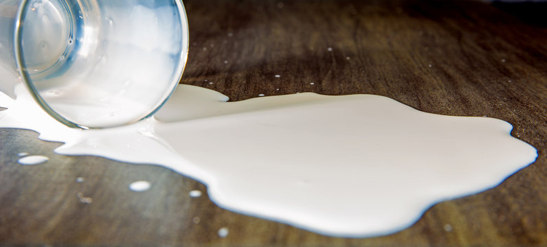 ein Glas mit versch&uuml;tteter Milch liegt auf einem Tisch