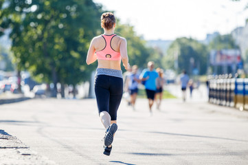 Fototapeta premium Slim woman running on the street in the morning. Healthy lifestyle background with jogging girl and copy space