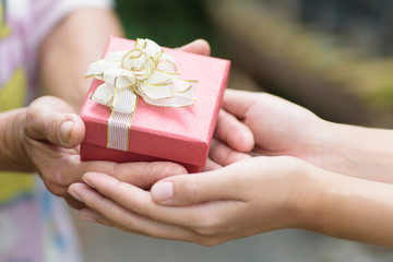 Red gift box in hand for giving in holidays