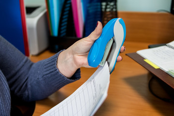 Hands holding stapler and paper.Lefty.Close up of a woman hands and holding a blue stapler in her...