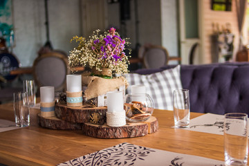 candles in the interior. home decor. candle and pine cones. Decorative white candles stand on a slice of wood. the country house decor is in the details.white - pink heather in autumn basket. wedding