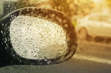 urban landscape in rainy weather with sunlight in rearview mirror 