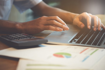 Close up business man hand doing finance and calculate on wooden table about cost at home office. accountant concept.