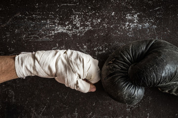 Old boxing glove against the boxing wraps is ready for fight. Dark background. Professional champion fight concept. Vintage retro style. Man's strength.