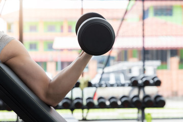 Obraz na płótnie Canvas Closeup of a young athlete man lifting weights at sport club