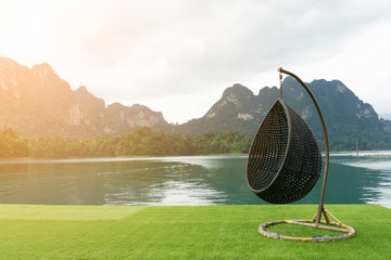 Wicker hanging chair swing hanging on a chain with beautiful mountains landscape