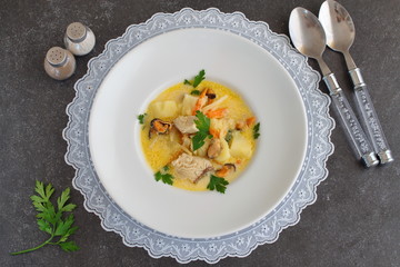 Creamy soup with fish fillet and mussles in a white plate on a white cloth on a grey abstract background. Healthy eating concept. Meditteranian lifestyle.