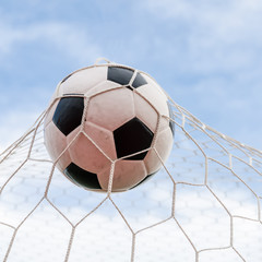 Soccer football in Goal net with the sky field.