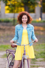 Fototapeta na wymiar Beautiful young woman with bicycle, outdoors