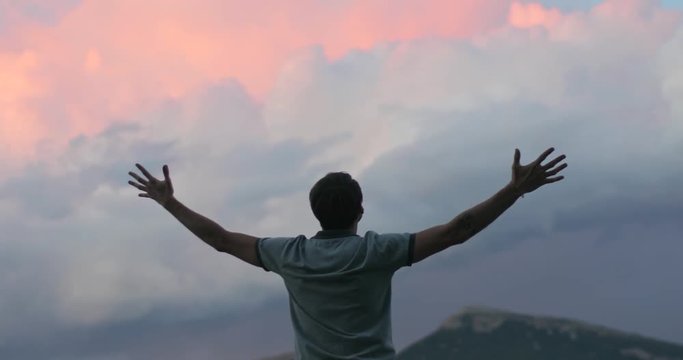 Man on top of mountain raising hands up 4k close up. Strong male silhouette in nature holds hands up expressing success reward determination achievement self-made person concept in Alps Europe