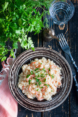Preparation of risotto with shrimps on a ceramic plate on a wooden table, top view