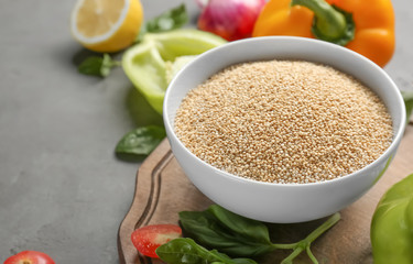 Raw quinoa in white ceramic bowl on kitchen table