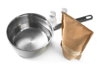 Composition with raw quinoa, saucepan, salt and pepper shakers on white background
