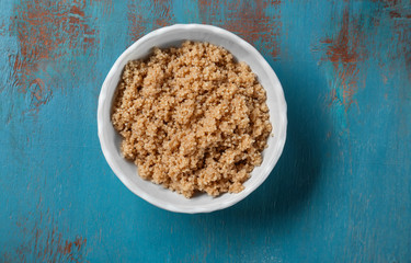Cooked quinoa in bowl on blue wooden background