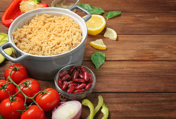Composition with cooked quinoa and fresh products on wooden background