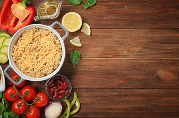Composition with cooked quinoa and fresh products on wooden background