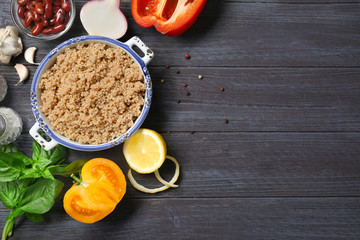 Composition with cooked quinoa and fresh products on wooden background