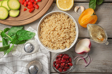 Composition with cooked quinoa and fresh products on wooden background