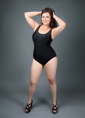 Obraz premium Beautiful overweight woman in black swimsuit on grey background
