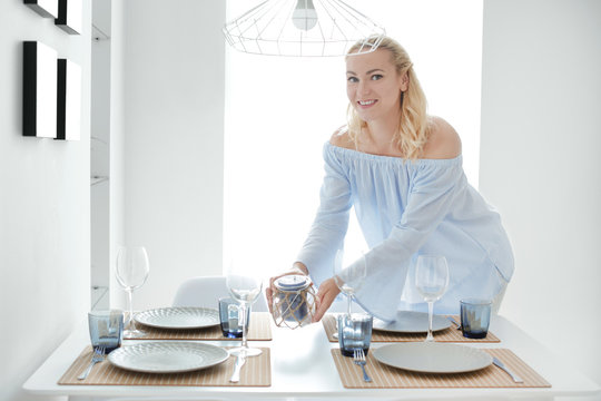 Beautiful Woman Laying Table In Kitchen At Home