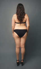 Naklejka premium Beautiful overweight woman in black bikini on grey background