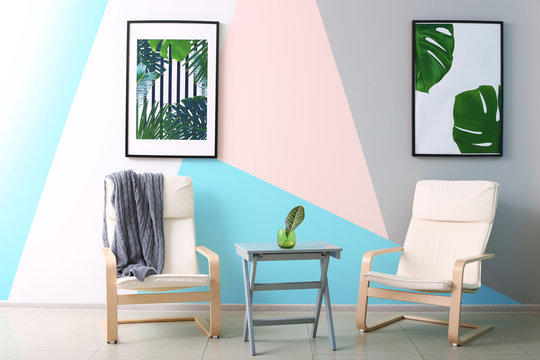 Modern room design with framed pictures of tropical leaves and two chairs