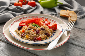 Salad with quinoa, tomato and pepper on wooden table