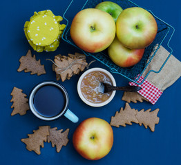 A cup of tea with jam, christmas tree cookies and apples on the dark blue background