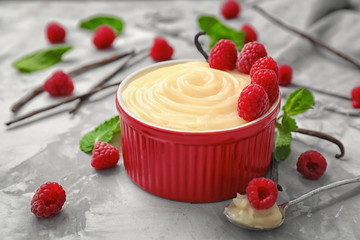 Composition with vanilla pudding, fresh mint and raspberries on grey background