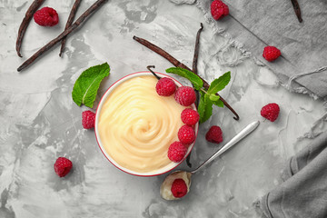 Composition with vanilla pudding, fresh mint and raspberries on grey background