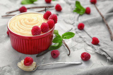 Composition with vanilla pudding, fresh mint and raspberries on grey background