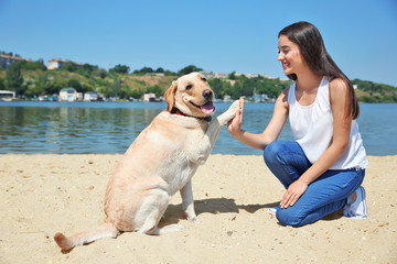 Young woman resting with yellow retriever near river