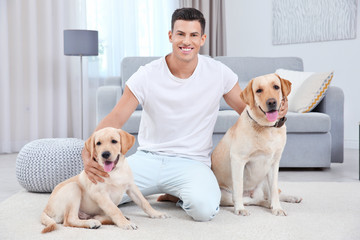 Young man resting with yellow retrievers at home