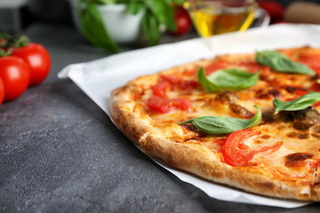 Delicious pizza with tomatoes and fresh basil on kitchen table