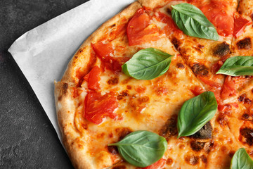 Delicious pizza with tomatoes and fresh basil on kitchen table