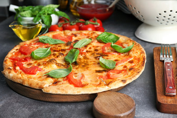 Delicious pizza with tomatoes and fresh basil on kitchen table