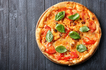 Delicious pizza with tomatoes and fresh basil on wooden background