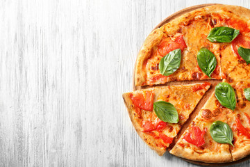Delicious pizza with tomatoes and fresh basil on wooden background