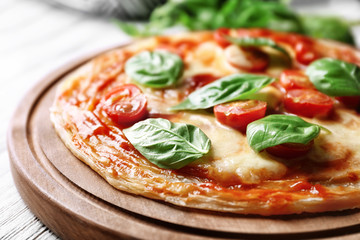 Delicious pizza with tomatoes and fresh basil on kitchen table