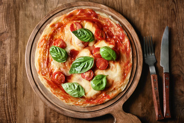 Delicious pizza with tomatoes and fresh basil on wooden background