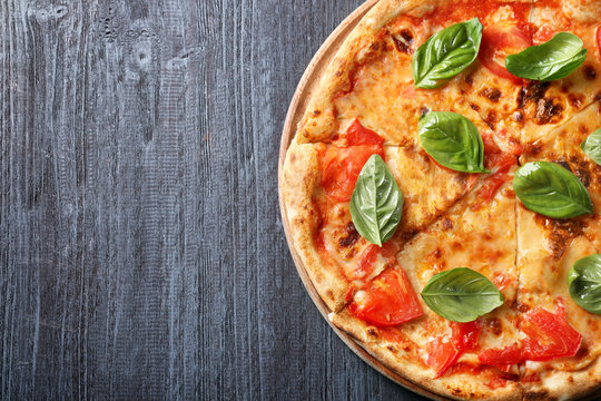 Delicious pizza with tomatoes and fresh basil on wooden background