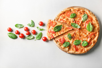 Composition with pizza, cherry tomatoes and fresh basil on light background