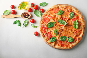 Composition with pizza, oil, cherry tomatoes and fresh basil on light background