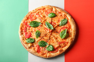 Delicious pizza with fresh basil on Italian flag on background