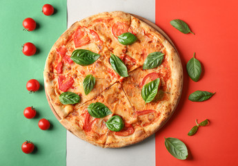 Composition with pizza, cherry tomatoes and fresh basil on Italian flag on background