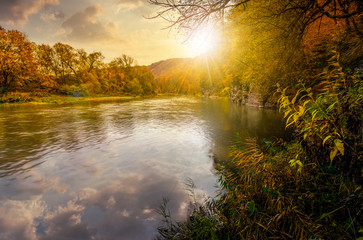 forest river in autumn mountains at sunset