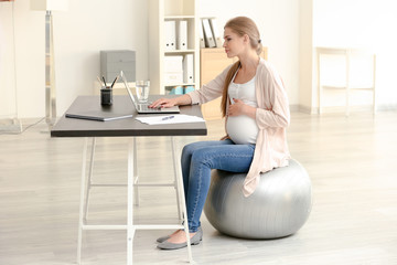 Young pregnant woman working in home office