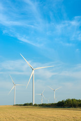 Fototapeta premium Wind mill in field with blue sky. Power and energy.