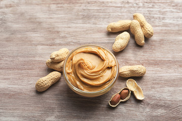 Glass bowl with peanut butter on wooden background